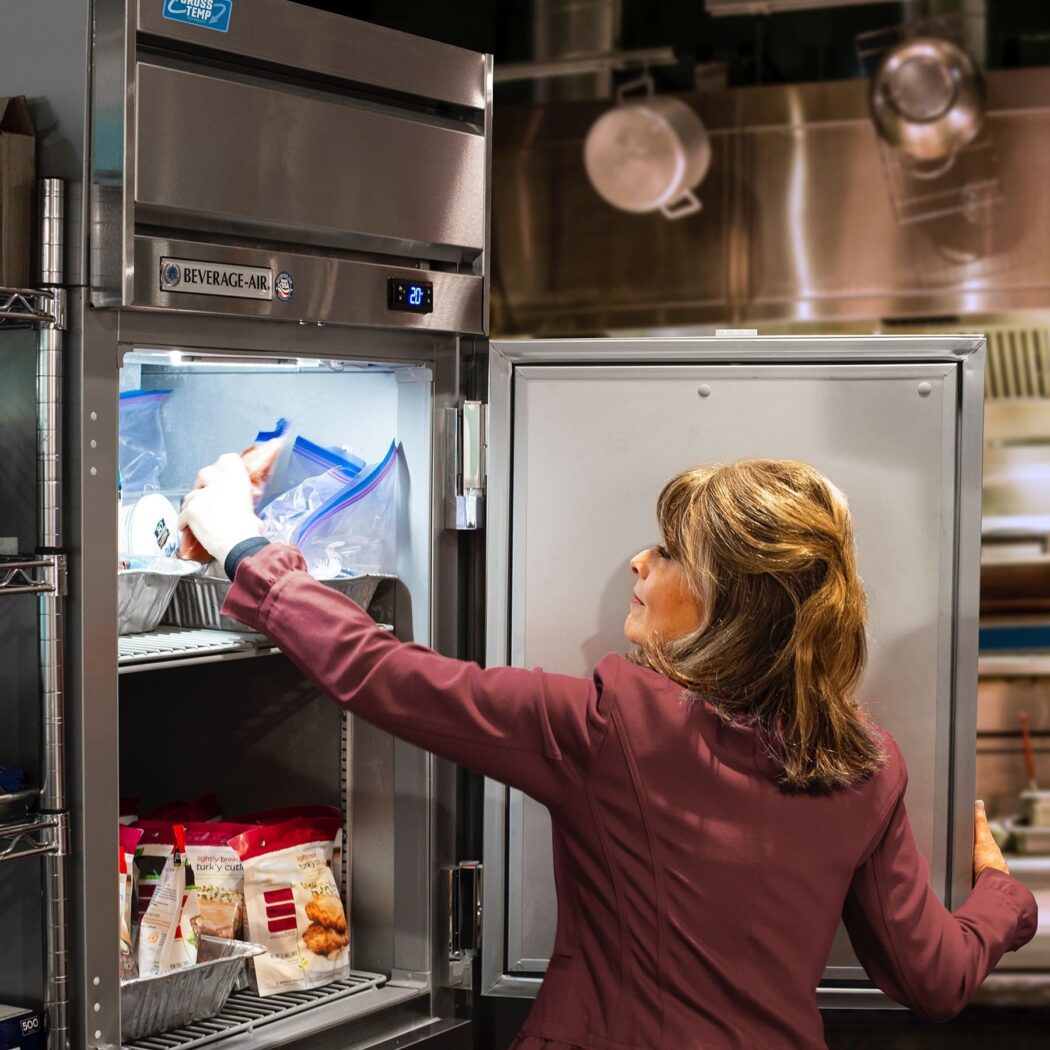 woman reaching into commercial beverage-air fridge.